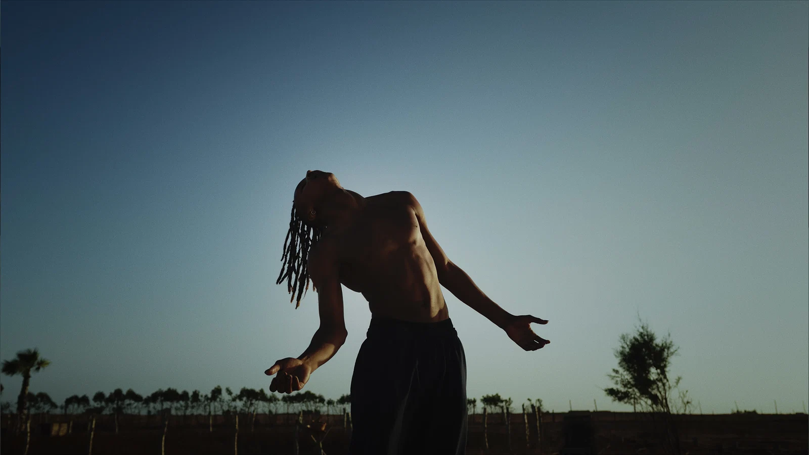 Finished-look still: performer against a dusk sky